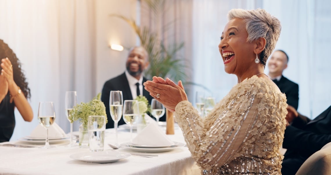 Woman clapping for a speaker at a table at a donor event