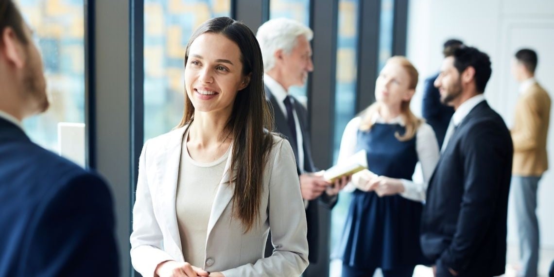 Woman in suit smiling at someone out of frame at an corporate event
